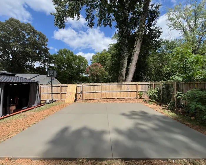 Wide finished concrete pad and driveway in a fenced back yard