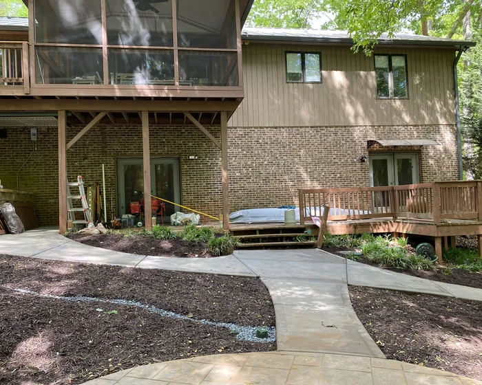 Concrete walkway curving from a driveway to the front steps of a brick home