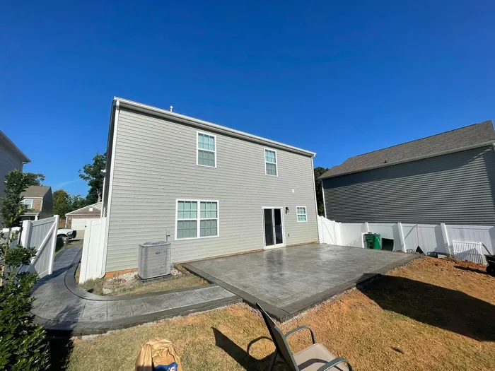 Poured concrete patio and driveway alongside a two story home